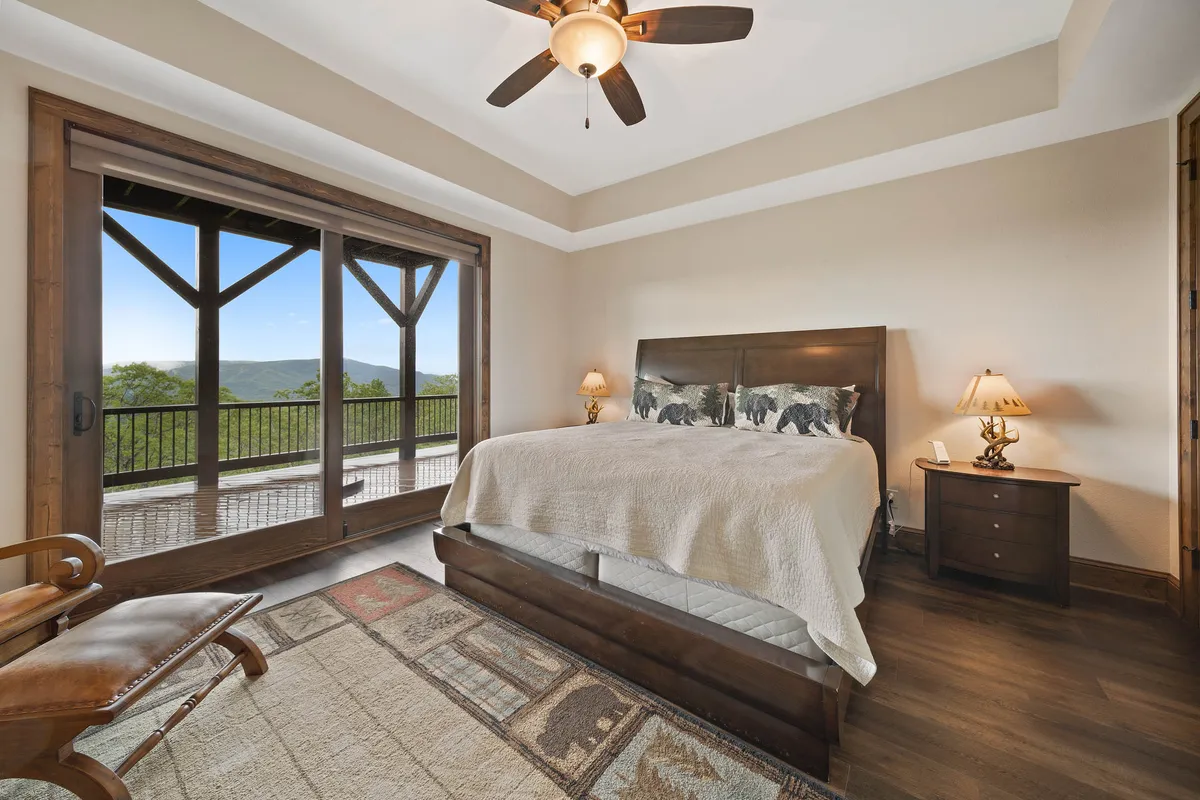 A serene studio apartment retreat with a king-sized bed adorned with animal-themed pillows, large sliding glass doors leading to a private balcony, and tranquil décor. The balcony offers a place for morning coffee or sunset views in complete privacy.