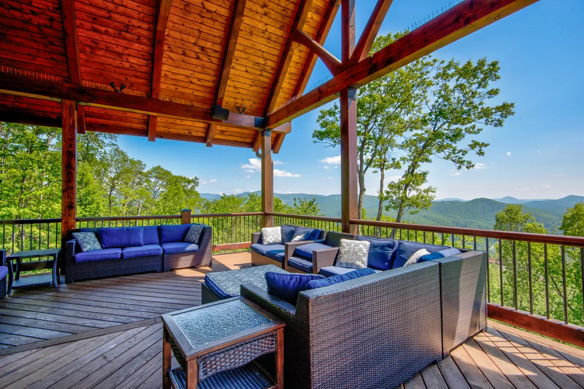 A stylish outdoor seating area with wooden beams, comfortable chairs, and a panoramic mountain view. The inviting setup encourages gatherings, relaxation, and taking in the natural beauty, evoking both private comfort and community spirit.