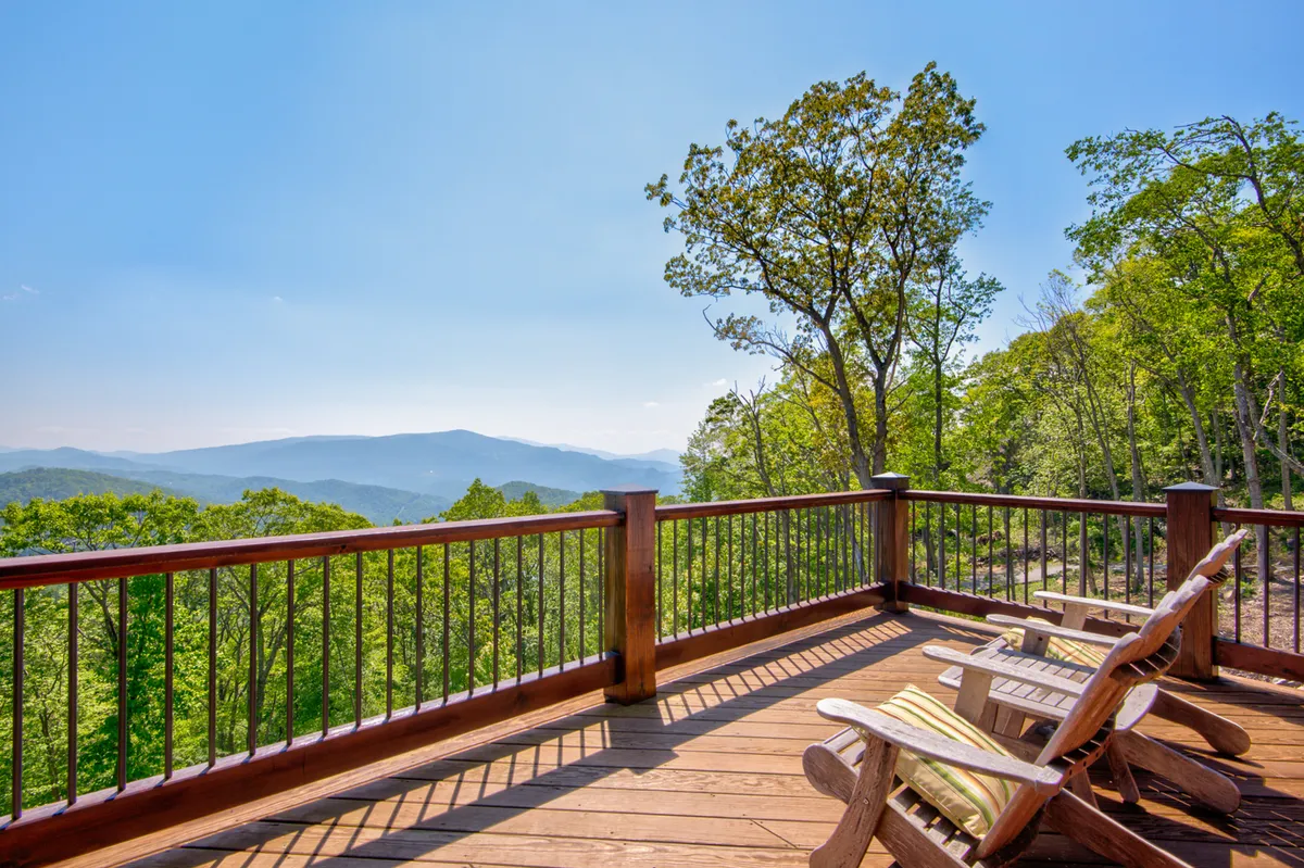 This exterior shot features a wooden deck with classic Adirondack chairs, overlooking a sweeping mountain vista. The serene environment is perfect for quiet reflection, small gatherings, or enjoying nature’s beauty. The mood is peaceful and the setting sun suggests opportunities for stargazing or intimate evenings outdoors.